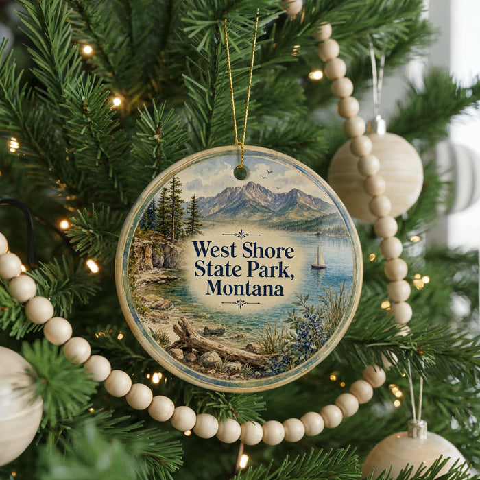 A round ornament hanging on a Christmas tree, featuring a scenic landscape with mountains, a lake, and a sailboat.