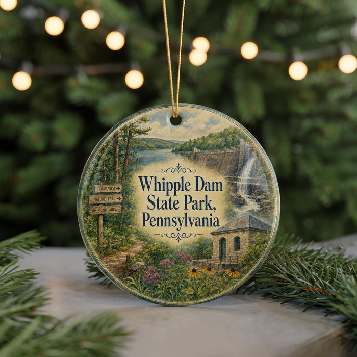 A round ornament with a scenic image of Whipple Dam State Park, Pennsylvania, hanging on a string.