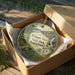 A circular ornament in a wooden box, featuring a scenic image of Whipple Dam State Park, Pennsylvania.