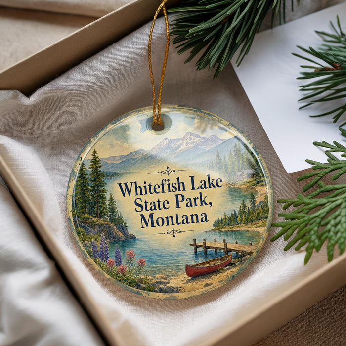 A decorative ornament with a scenic image of Whitefish Lake State Park, Montana, featuring a lake, mountains, pine trees, and a canoe.