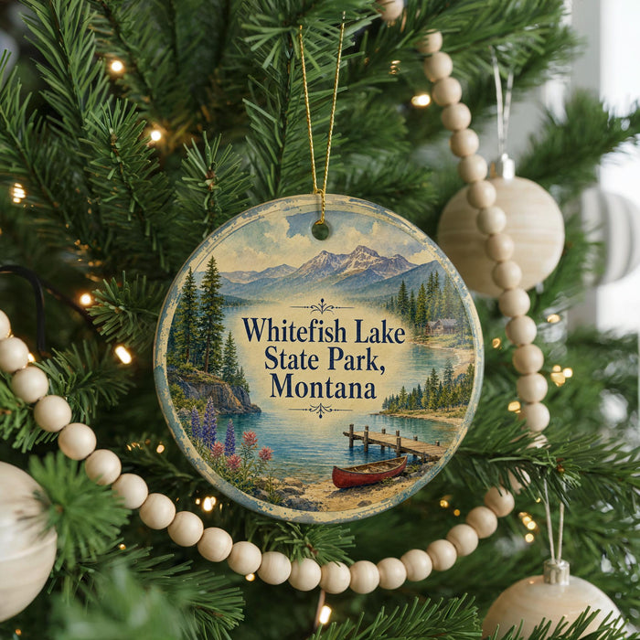 A round ornament hanging on a Christmas tree, featuring a scenic landscape with mountains, pine trees, and a lake.