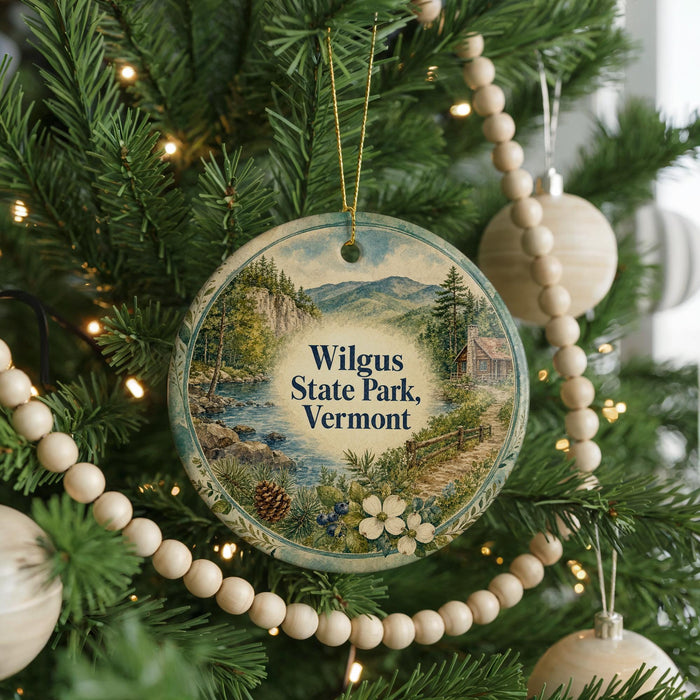 A round ornament hanging on a Christmas tree, featuring a scenic landscape of Wilgus State Park, Vermont.