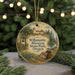 A round ornament with a painting of a rural scene, featuring a bell tower, a church, and a river, hanging from a string.