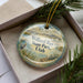A round ornament with a scenic image of Willard Bay State Park, Utah, displayed in a box with pine branches.