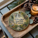 A wooden tray with a decorative ornament featuring a scenic image of Willow River State Park, Wisconsin, and pine cones.
