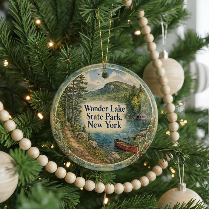 A round ornament on a Christmas tree, featuring a scenic landscape with a lake, mountains, and a red boat, with the text "Wonder Lake State Park, New York" displayed on it.