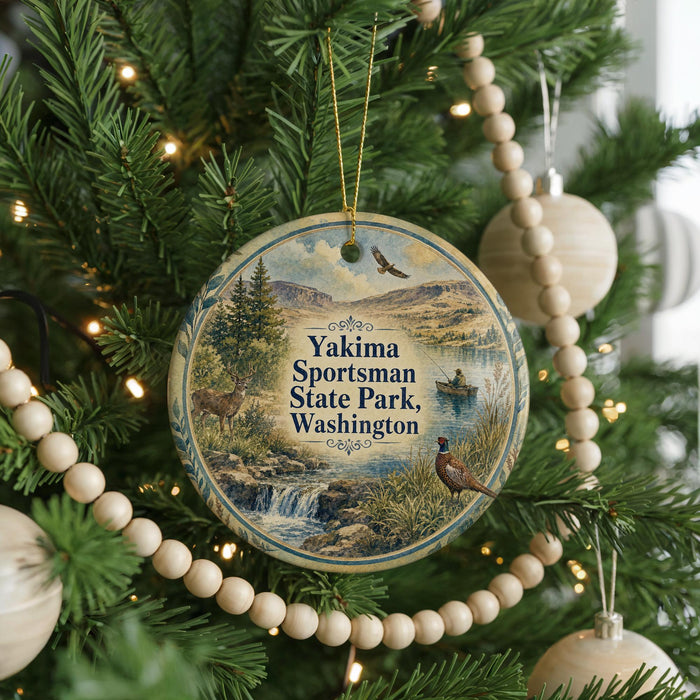 A circular ornament hanging on a Christmas tree, featuring a scenic landscape with a waterfall, pine trees, and a bird.