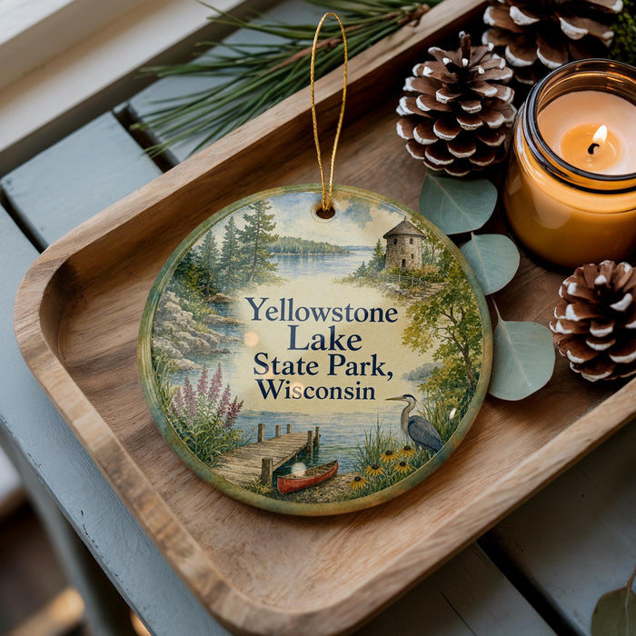 A decorative ornament featuring a scenic landscape of Yellowstone Lake, State Park, Wisconsin, with pine cones and a candle on a wooden tray.