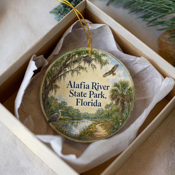 A circular ornament with a scenic image of the Alafia River State Park in Florida, featuring a bird, palm trees, and a path along the river.