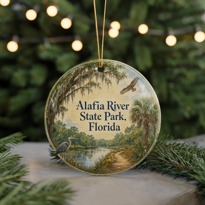 A circular ornament with a scenic image of the Alafia River State Park in Florida, featuring a bird, palm trees, and a path along the river.