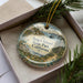 A decorative ornament in a box, featuring a scenic image of Angel Island, California.