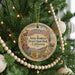 A round ornament hanging on a Christmas tree, featuring a desert landscape with mountains and cacti.