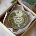 A decorative ornament in a box, featuring a scenic landscape with a river, trees, and mountains.