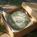 A decorative ornament in a box, featuring a scenic image of Argyle Lake State Park in Illinois.