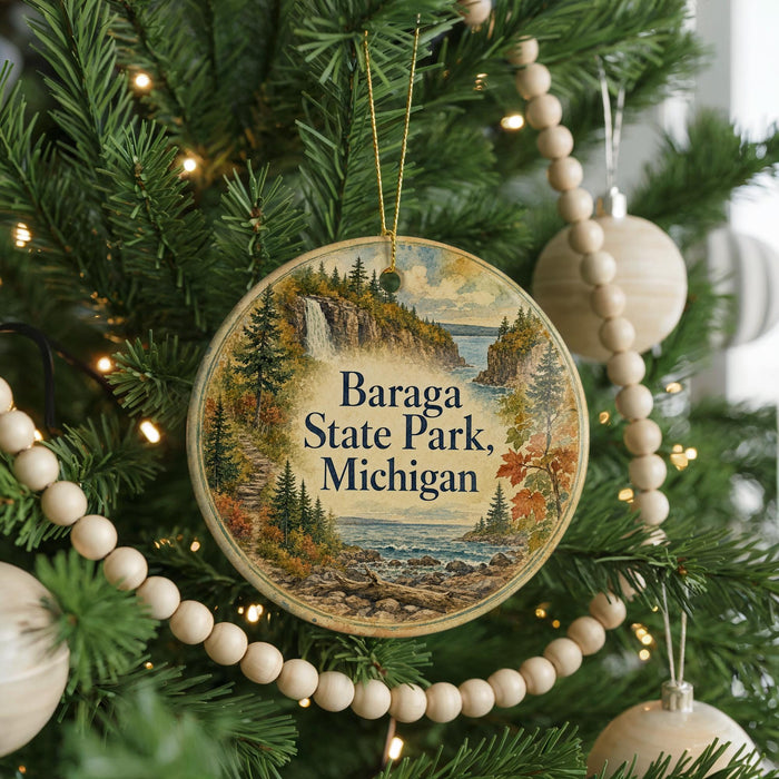 A circular ornament hanging on a Christmas tree, featuring a scenic landscape with a waterfall and pine trees.
