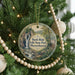 A circular ornament hanging on a Christmas tree, featuring a scenic image of a waterfall surrounded by lush greenery.