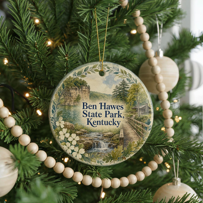 A round ornament on a Christmas tree, featuring a scenic landscape with a waterfall and a bridge, with the text "Ben Hawes State Park, Kentucky" displayed on it.