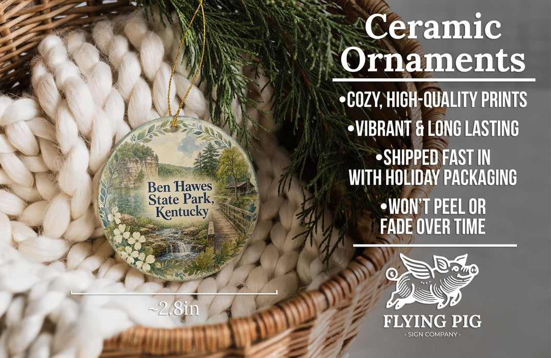 Ceramic ornaments, featuring a Ben Hawes State Park, Kentucky ornament, are displayed in a basket with pine branches. The text highlights the ornament's features, such as its coziness, high-quality prints, vibrant and long-lasting vibrancy, fast shipping, holiday packaging, and the fact that it won't peel or fade over time.