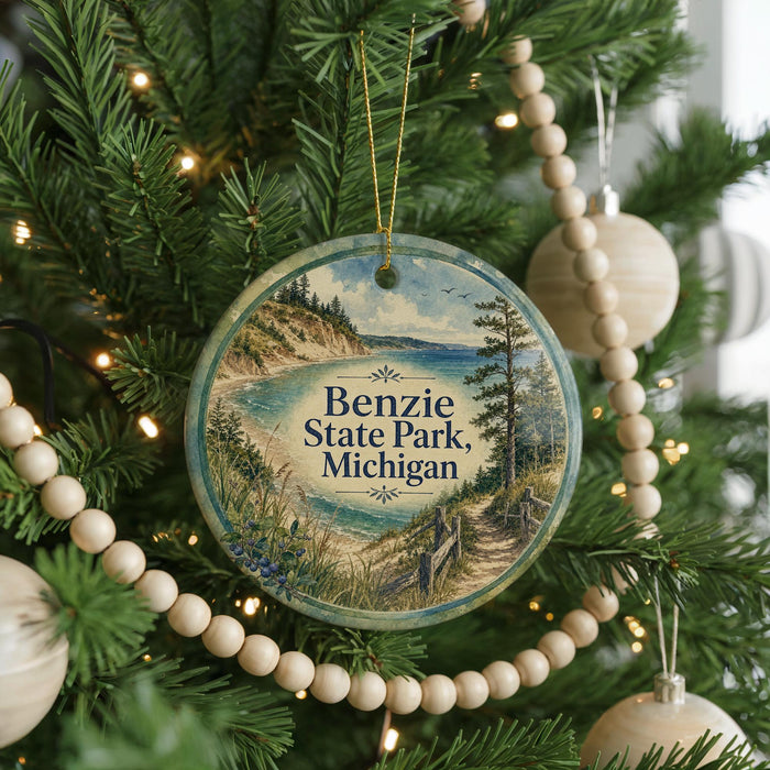 A round ornament hanging on a Christmas tree, featuring a scenic landscape with a lake and mountains.