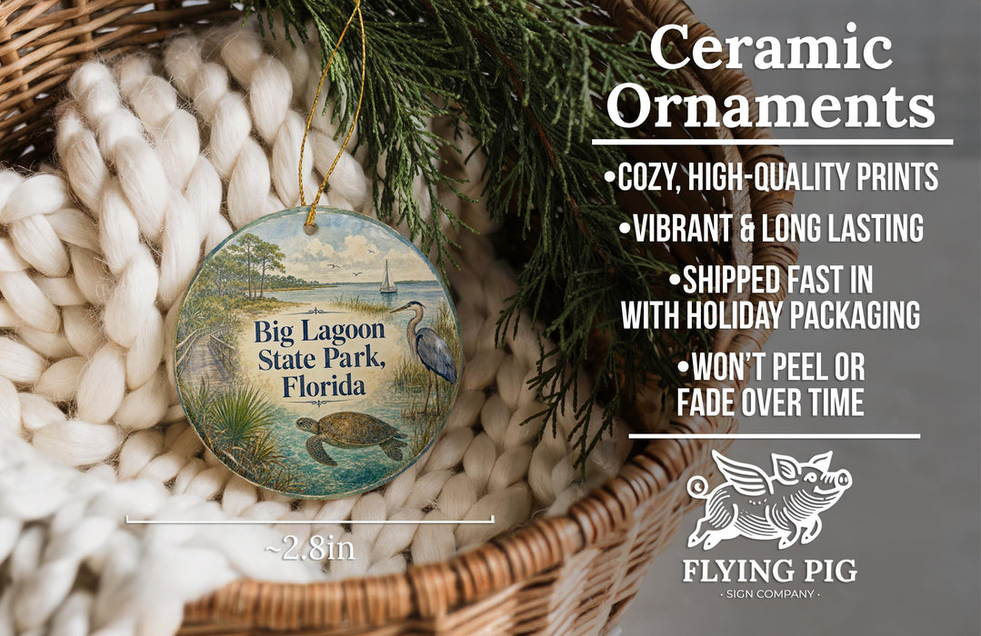 Ceramic ornaments, featuring a bird and a landscape, are displayed in a basket with pine branches.