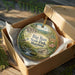 A decorative ornament in a box, featuring a scenic landscape with a bird, deer, and a cabin, along with the text "Big Run State Park, Maryland".