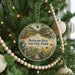 A round ornament hanging on a Christmas tree, featuring a scenic image of the Blackwater River State Park in Florida.