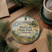 A round ornament with a scenic landscape of Boyd Lake State Park, Colorado, featuring a sailboat, mountains, and pine trees.