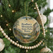 A round ornament hanging on a Christmas tree, featuring a scenic landscape of mountains and a lake.