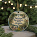 A round ornament with a scenic landscape and text, hanging on a string.