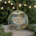A round ornament with a scenic image of a river and a bird, surrounded by greenery, is displayed in front of a blurred background with twinkling lights.