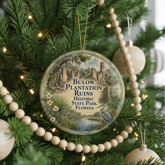 A round ornament hanging on a Christmas tree, featuring an illustration of a bird and palm trees, with text that reads "Bulow Plantation Ruins Historic State Park, Florida".