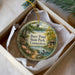 A decorative ornament in a box, featuring a scenic image of a lake, trees, and a bird, with the text "Burr Pond State Park, Connecticut" printed on it.
