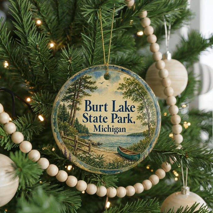 A round ornament hanging on a Christmas tree, featuring a scenic image of a lake and a canoe.