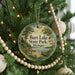 A round ornament hanging on a Christmas tree, featuring a scenic image of a lake and a canoe.