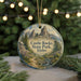A round ornament with a scenic landscape of Castle Rocks State Park, Idaho, featuring a mountain range and a stream, is displayed on a table with pine branches and twinkling lights in the background.