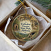 A circular ornament with a scenic image of the Cathedral Caves State Park in Alabama, displayed in a box with a white tissue paper lining.