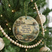 A round ornament hanging on a Christmas tree, featuring an illustration of a house and palm trees, with the text "Cedar Key Museum State Park, Florida" displayed on it.