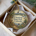 A decorative ornament in a box, featuring a scenic landscape with mountains, a lake, and various wildlife elements such as birds and deer.