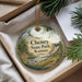 A decorative ornament with the text "Cheney State Park, Kansas" on it, hanging from a string. The ornament is placed in a box with pine branches and a white card.