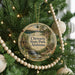 A round ornament hanging on a Christmas tree, featuring a scenic landscape with a waterfall and forest.