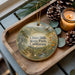 A wooden tray with a decorative ornament featuring a scenic landscape of Chino Hills State Park, California, and pine cones.