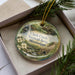 A decorative ornament in a box, featuring a scenic image of Clark Creek Natural Area in Mississippi.