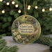 A round ornament with a scenic image of Clark Creek, surrounded by greenery, is displayed in front of a blurred background with twinkling lights.