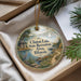 A decorative ornament with a scenic landscape featuring a lake, a boat, and a path, hanging from a string.