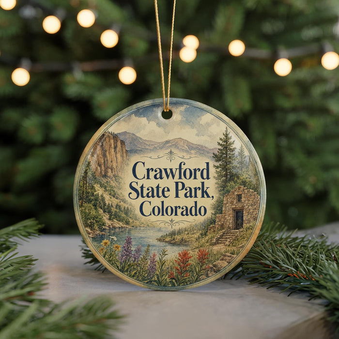 A circular ornament featuring a scenic landscape of Crawford State Park, Colorado, with a mountain backdrop and a river.