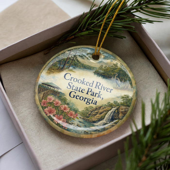 A decorative ornament with a scenic landscape of Crooked River State Park, Georgia, featuring a waterfall, pine trees, and flowers.