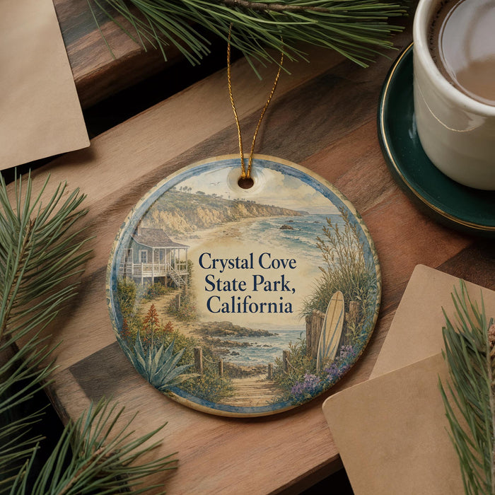 A decorative ornament featuring a scenic coastal landscape with a house, palm trees, and a beach, hanging on a wooden surface.