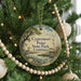 A round ornament hanging on a Christmas tree, featuring a scenic image of a bird, a pond, and a bridge.