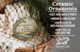Ceramic ornaments, featuring a bird and a landscape, are displayed in a basket with pine branches.