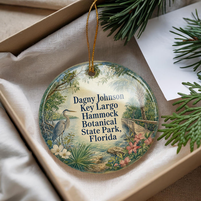 A decorative ornament with a bird and tropical foliage, placed in a box with pine branches.